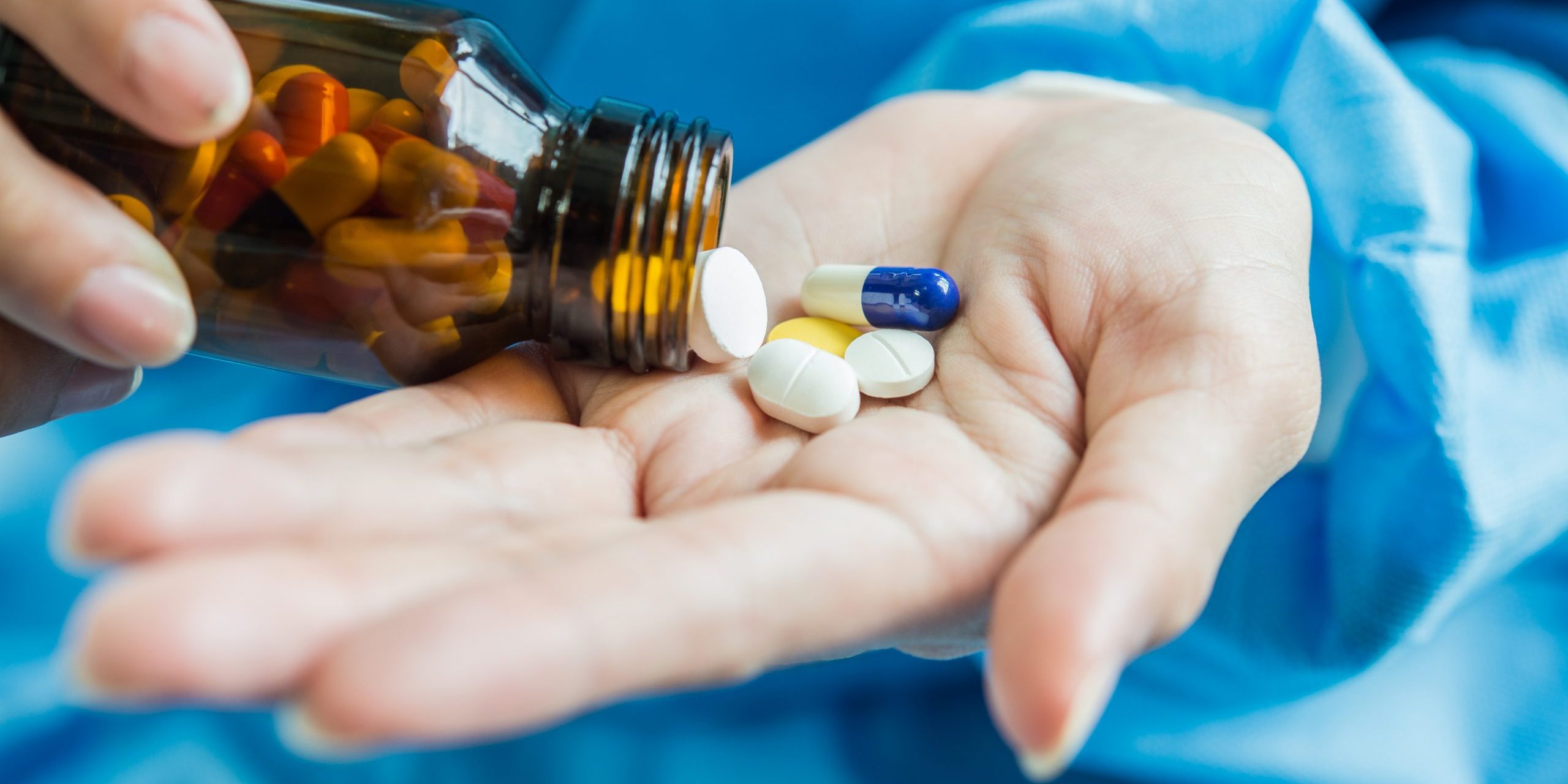 Woman’s hand pours the medicine pills out of the bottle