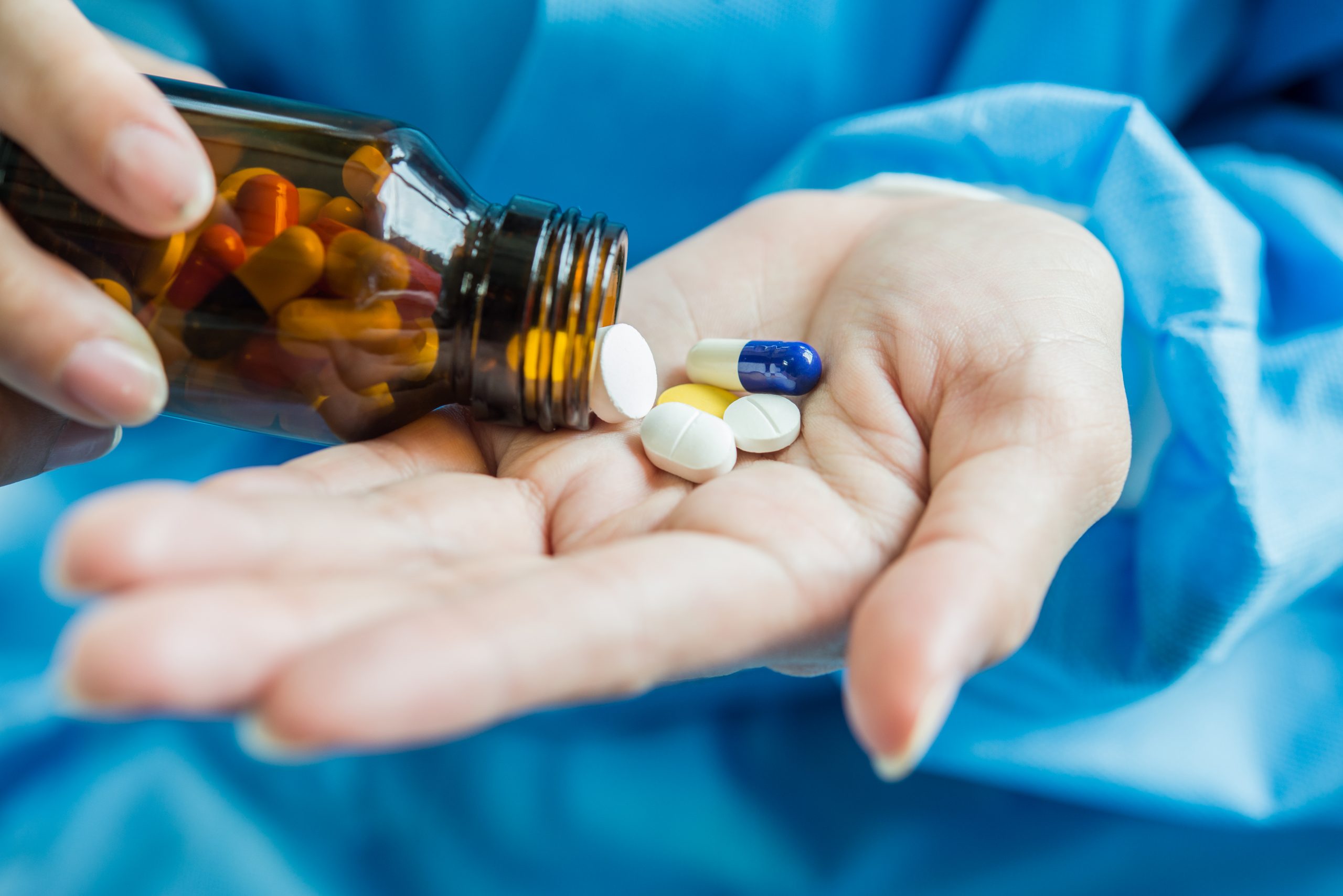 Woman’s hand pours the medicine pills out of the bottle