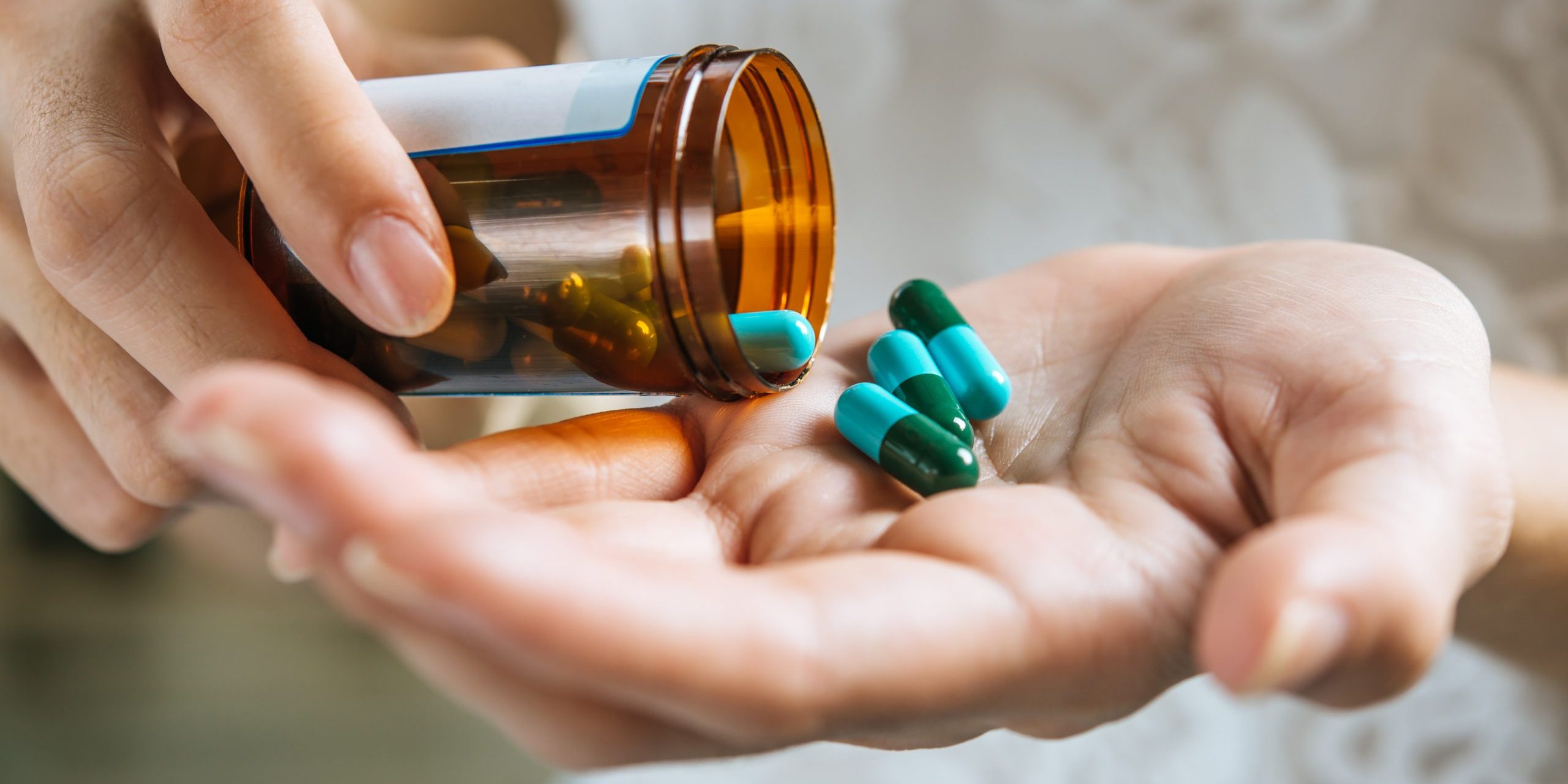 Woman’s hand pours the medicine pills out of the bottle