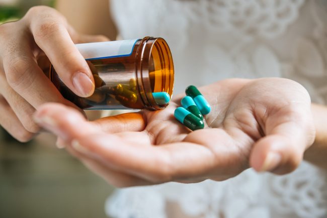 Woman’s hand pours the medicine pills out of the bottle