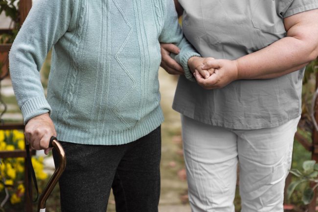 front-view-female-nurse-helping-senior-woman-walk