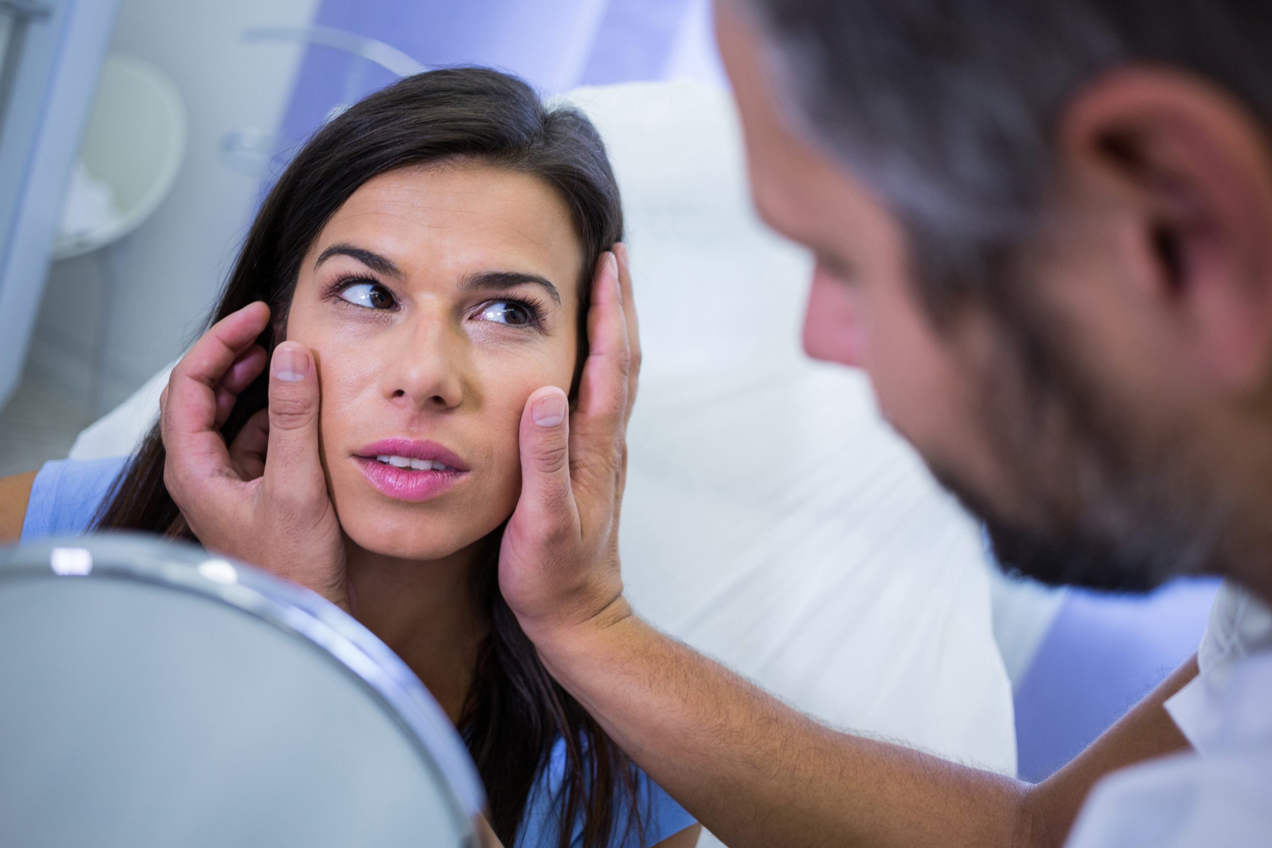 Doctor checking patients skin after cosmetic treatment at clinic