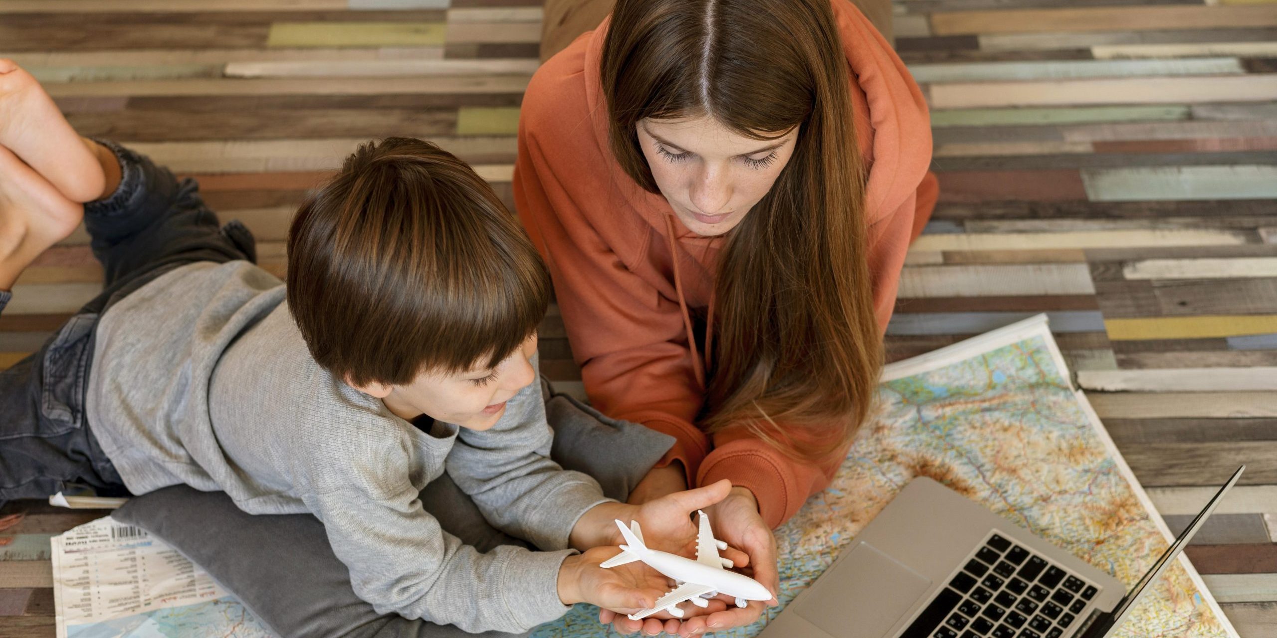 mae-e-filho-em-casa-com-laptop-e-mapa-procurando-um-lugar-para-viajar