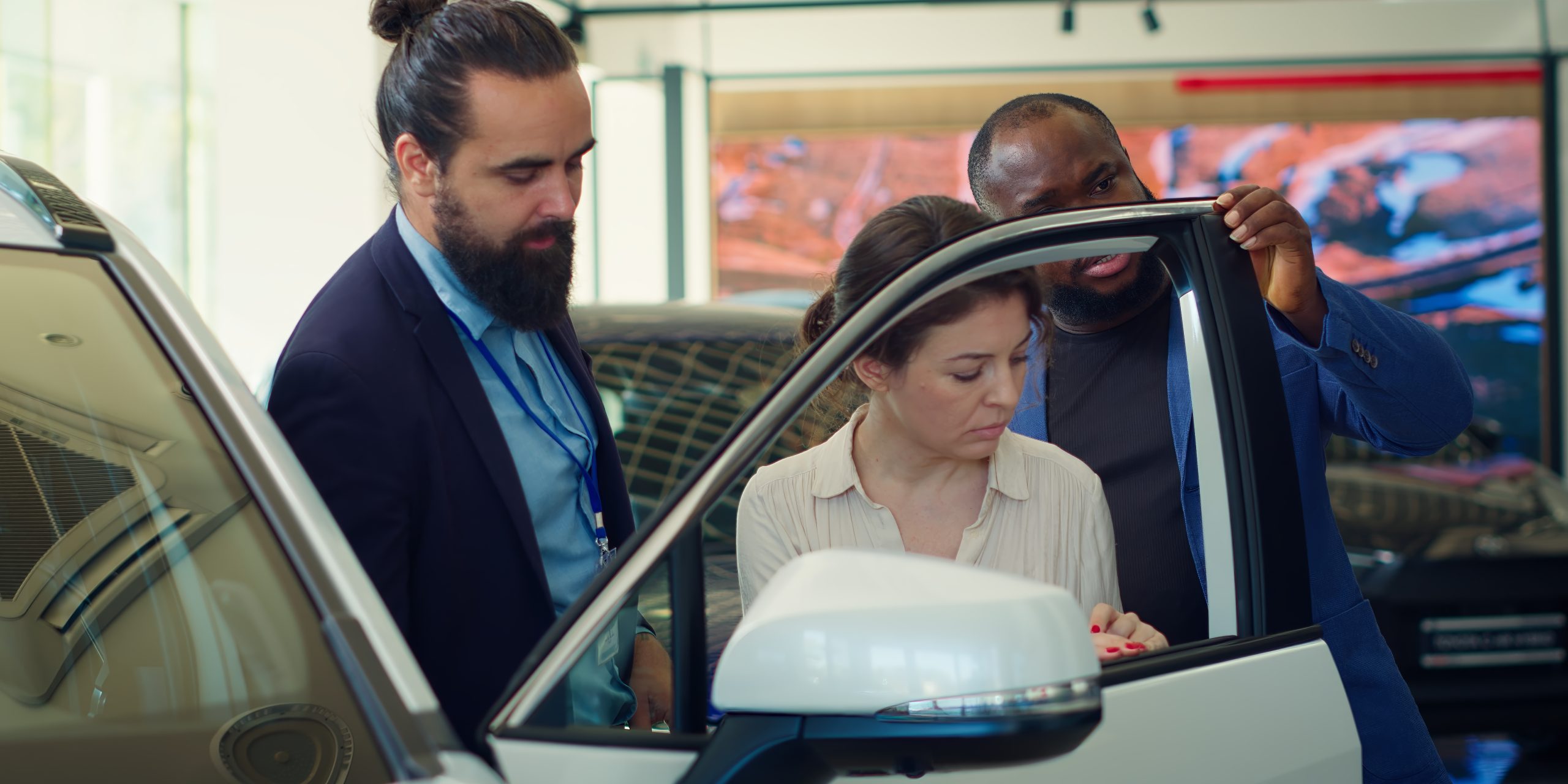 Car dealership agent demonstrating vehicle door durability to clients