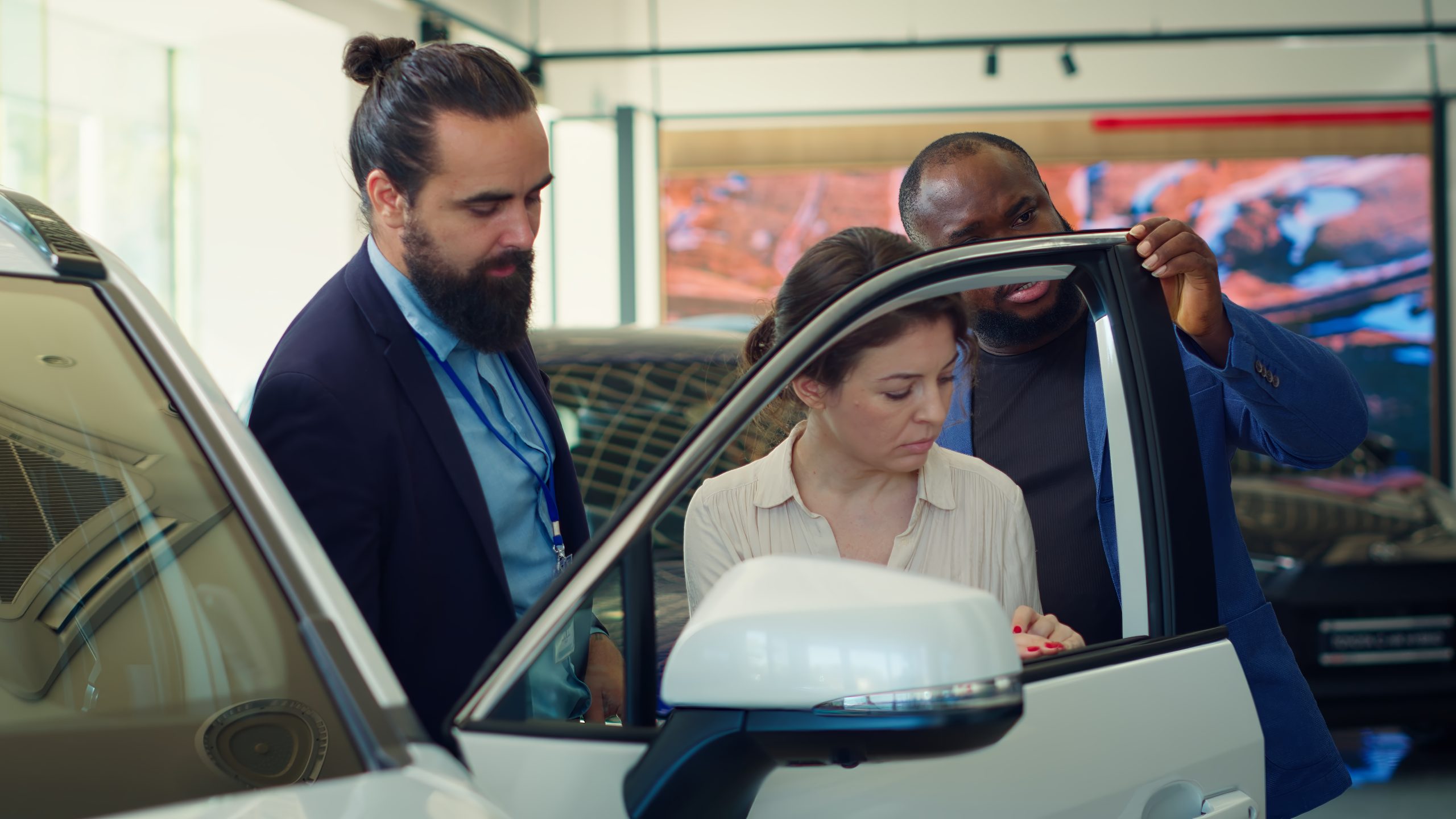 Car dealership agent demonstrating vehicle door durability to clients